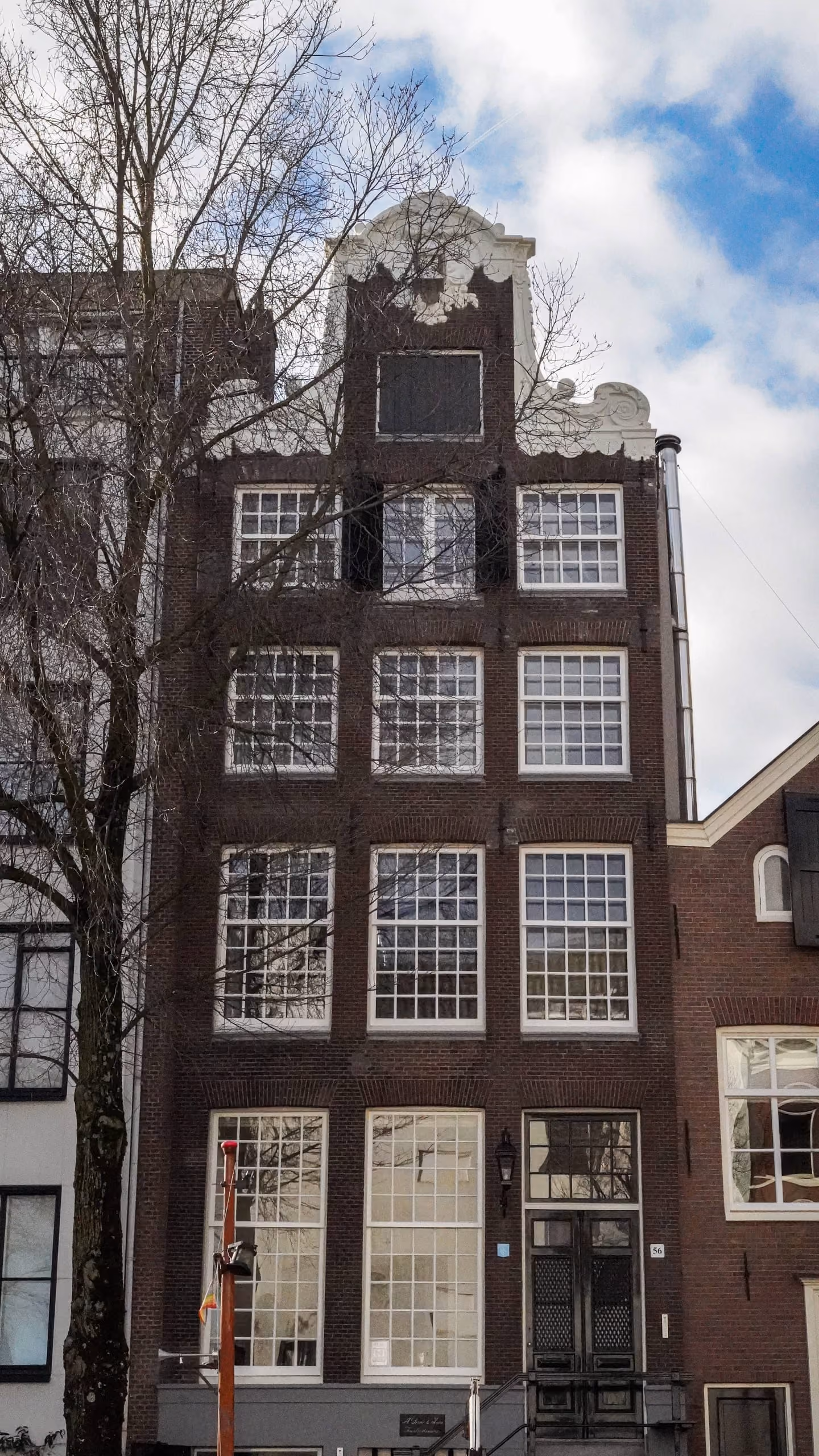 Bakstenen grachtenpandgevel met witte kozijnen in Amsterdam