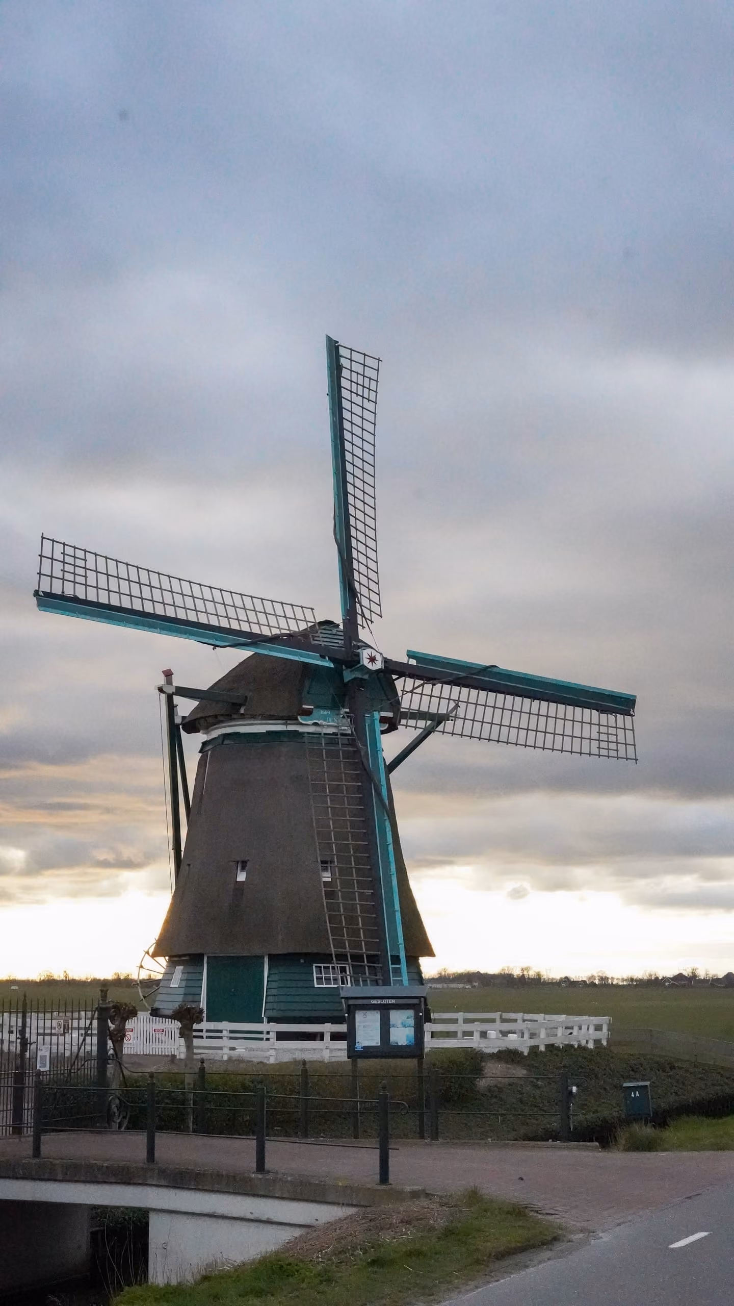 Poldermolen met groen geschilderde wieken tegen de avondlucht